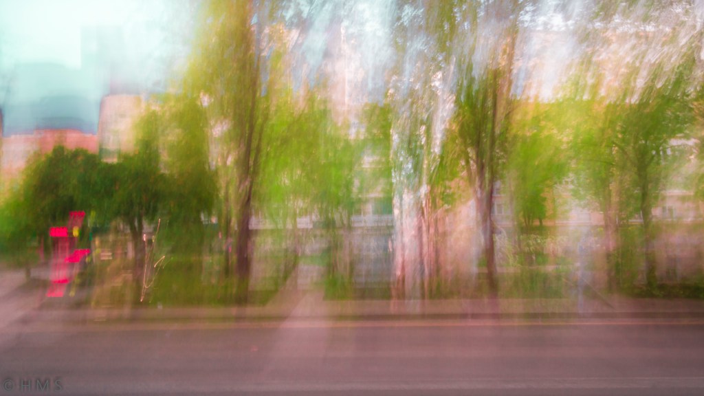 Abstract ICM photograph of trees and city buildings blending into soft green and orange tones — fine art long-exposure by Héctor Morón.